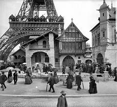 old image of building and base of eiffel tower with people